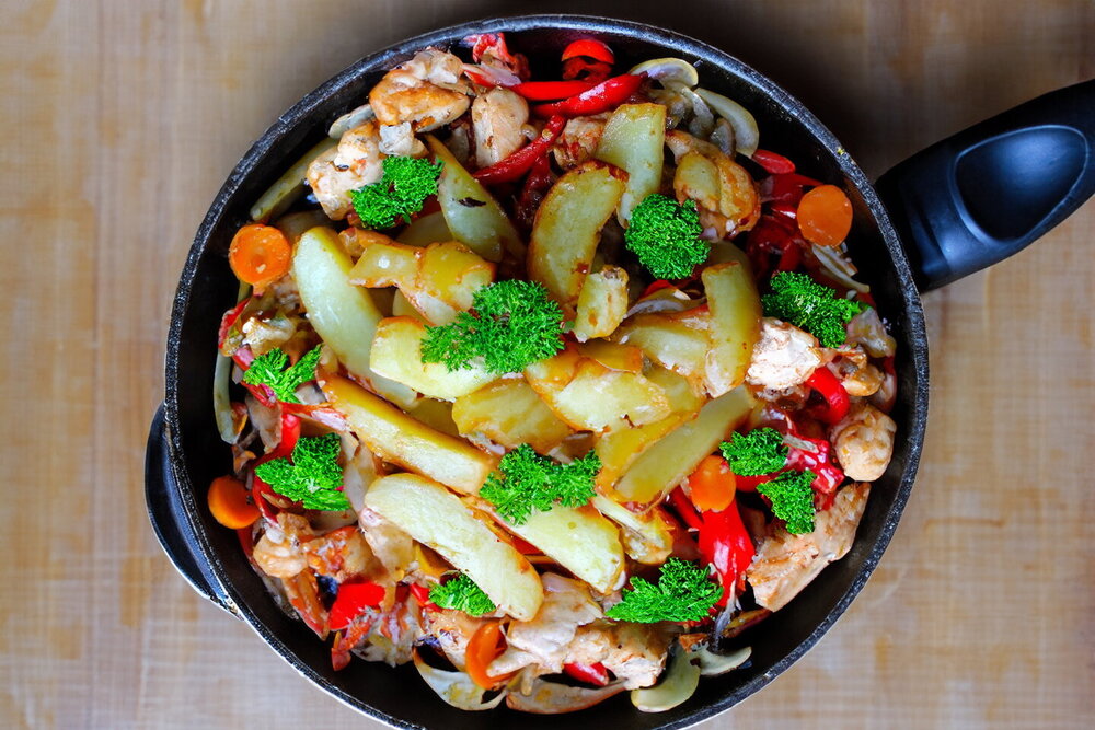 Chicken with Vegetables in a Skillet over a Campfire